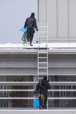 Sundsvall, İsveç. İki adam bir binanın çatısından buz ve kar kaldırıyor..