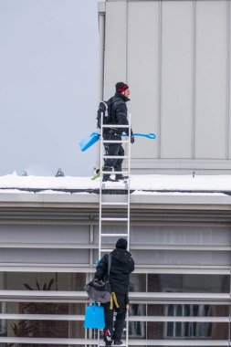 Sundsvall, İsveç. İki adam bir binanın çatısından buz ve kar kaldırıyor..