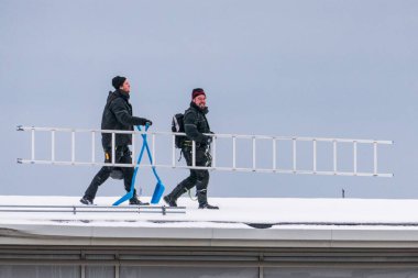 Sundsvall, İsveç. İki adam bir binanın çatısından buz ve kar kaldırıyor..