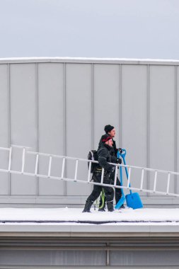 Sundsvall, İsveç. İki adam bir binanın çatısından buz ve kar kaldırıyor..