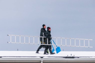 Sundsvall, İsveç. İki adam bir binanın çatısından buz ve kar kaldırıyor..