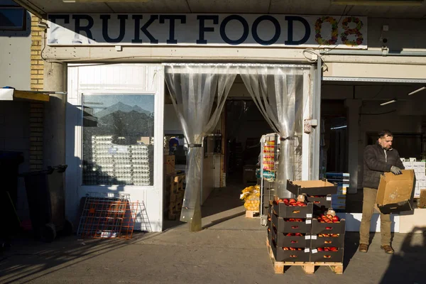 瑞典斯德哥尔摩一名男子在一家蔬菜批发商的店面和一箱西红柿旁 — 图库照片