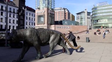 Oslo, Norveç Tren istasyonundaki merkez meydandaki insanlar ve ünlü kaplan heykeli. 