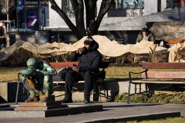 Oslo, Norveç 'te bir adam bir bankta oturmuş çıplak bir adamın heykelinin yanında bira içiyor ve 1958' den kalma bir bronz şarabı Per Palle Storm 'dan içiyor..
