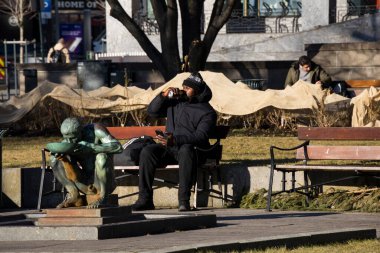 Oslo, Norveç 'te bir adam bir bankta oturmuş çıplak bir adamın heykelinin yanında bira içiyor ve 1958' den kalma bir bronz şarabı Per Palle Storm 'dan içiyor..