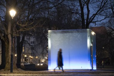 Oslo, Norveç yayaları Grunerlokka bölgesindeki Sofienberg Parkı 'nda mavi ışık kübünün önünde yürürler..