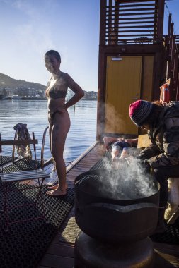 Oslo, Norveç Limandaki bir saunada sıcak bir saunadan sonra buz gibi denizde yıkanan insanlar.