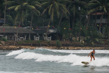 Hiriketiya Sahili, Sri Lanka Sörfçü Turistler dalgalarda sörf yapıyor.