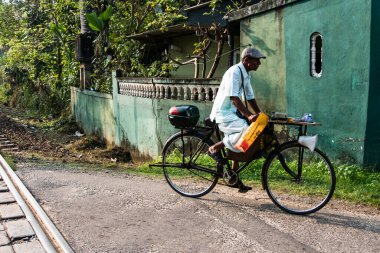 Unawatuna, Sri Lanka Yerli bir adam yeşil bir evin önünden bisikletle geçiyor.