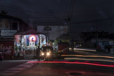 Unawatuna, Sri Lanka Bir Buddah heykeli ana yolun kenarında duruyor Bir tuk tuk taksisi ve trafik çizgileri ile.