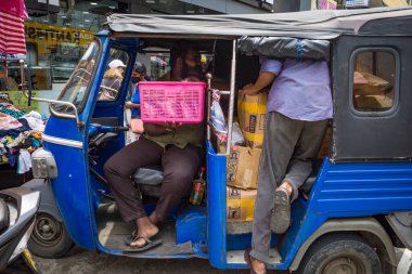 Galle ve Sri Lanka erkekleri pazardan alışveriş yapan bir tuktuk taksisine doluşuyorlar..