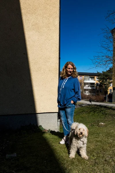 Stockholm, İsveç Bir kadın bir binanın yanında bir Bichon kaka köpeğiyle duruyor.
