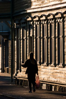 Vanersborg, İsveç. Bir kadın arka sokaktaki batan güneşe doğru yürüyor. Eski binaların cephesi boyunca..