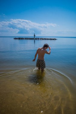 Point Lookout, Maryland USA Güneşli bir günde genç bir adam Chesapeake Körfezi 'nde yüzüyor..