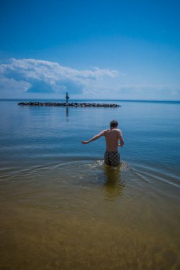 Point Lookout, Maryland USA Güneşli bir günde genç bir adam Chesapeake Körfezi 'nde yüzüyor..