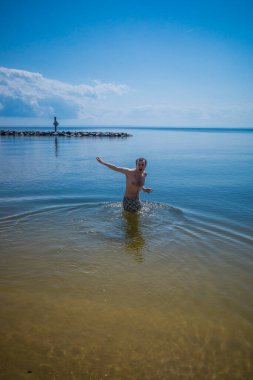 Point Lookout, Maryland USA Güneşli bir günde genç bir adam Chesapeake Körfezi 'nde yüzüyor..