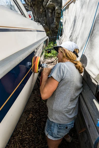 Stockholm, İsveç Bir kadın motorlu teknenin kenarına ağda yapmak için elektrikli bir alet kullanır.