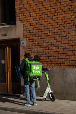 Stockholm, İsveç. Sokakta elektrikli scooterlı bir Bolt yiyecek dağıtıcısı..
