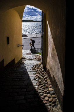 Stockholm, İsveçli yayalar Birger Jarl 'ın Kulesi' nin kapısından görünen Riddarholmen adasında yürürler.