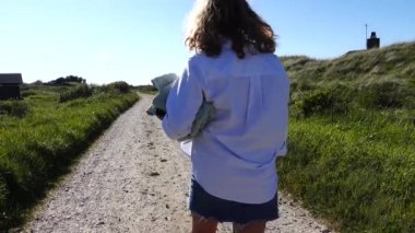 Hirtshals, Danimarka 'da bir kadın kumsala kirli bir yolda havluyla yürür.