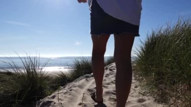 Hirtshals, Danimarka 'da bir kadın kumsala kirli bir yolda havluyla yürür.