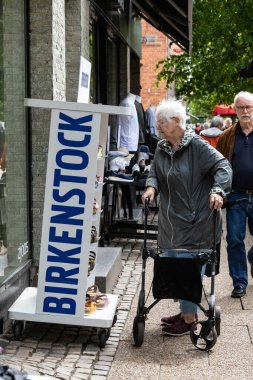 Hjorring, Danimarka. Yürüteçli son sınıf bir kadın bir ayakkabı mağazasında Birkenstock vitrinine bakıyor..