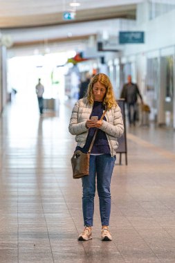 Aalborg, Danimarka Havaalanı terminalinde bir kadın telefonuna bakıyor..