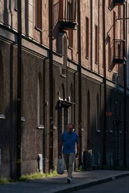 Stockholm, İsveç Kungsholmen 'de Grubbens Gata' da batan güneşte yürüyen bir adam..