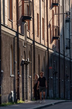 Stockholm, İsveç Kungsholmen 'de Grubbens Gata' da batan güneşte yürüyen bir çift..