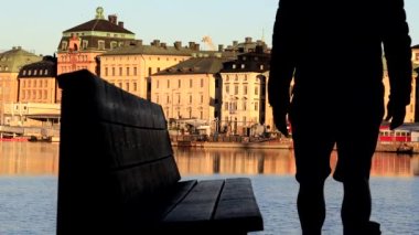 Stockholm, İsveç 'te bir adam Skeppsholmen' de su manzaralı bir bankta oturuyor ve Gamla Stan, ya da Old Town. 