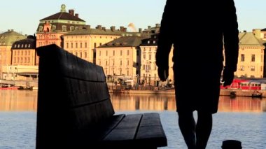 Stockholm, İsveç 'te bir adam Skeppsholmen' de su manzaralı bir bankta oturuyor ve Gamla Stan, ya da Old Town. 