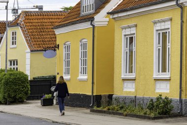 Skagen, Danimarka Sarı evleri olan bir kadın sokakta yürüyor.