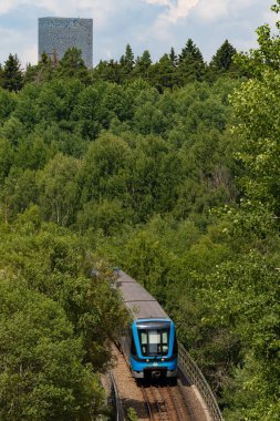 Stockholm, İsveç Kista ve Kista Kulesi 'ndeki yüksek raylar üzerinde bir tünel veya metro treni yolculuk eder..