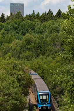 Stockholm, İsveç Kista ve Kista Kulesi 'ndeki yüksek raylar üzerinde bir tünel veya metro treni yolculuk eder..