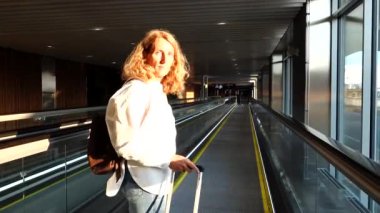 Stockholm, İsveç. Bir kadın Arlanda havaalanında yürüyen merdivene el çantası ile biniyor..