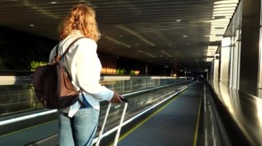 Stockholm, İsveç. Bir kadın Arlanda havaalanında yürüyen merdivene el çantası ile biniyor..