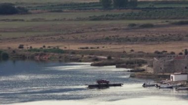 Arnavutluk 'un Ksamil kentinde Butrint Gölü Ulusal Parkı yakınlarındaki Butrint Gölü girişinden küçük bir teleferikli feribot geçiyor. 