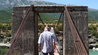 Permet, Arnavutluk Bir adam Vjosa nehri üzerindeki eski bir tahta ve kablo köprü üzerinden yürüyor