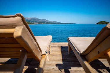 Ksamil, Arnavutluk 'un güverte sandalyeleri masmavi suya bakan bir iskelede.