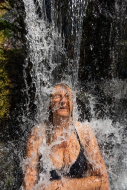 Permet, Albania A woman sits undera waterfall at the Benja Thermal Baths in the mountains.