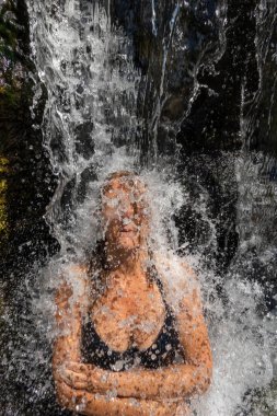 Permet, Albania A woman sits undera waterfall at the Benja Thermal Baths in the mountains.