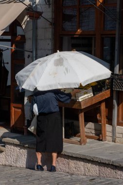 Gjirokaster, Albania July 20, 2022 A senior woman buying fruit at a small store.