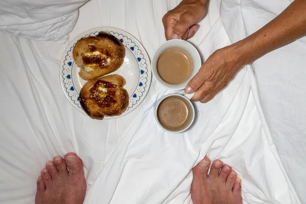 A coouple have toast and coffee in bed