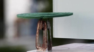 A burning anti-mosquito coil on a stand outdoors and smoke