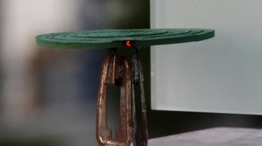 A burning anti-mosquito coil on a stand outdoors and smoke