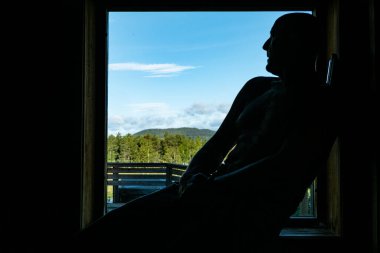 Sorsele,Sweden A man in a sauna with a window over Swedish Lappland.