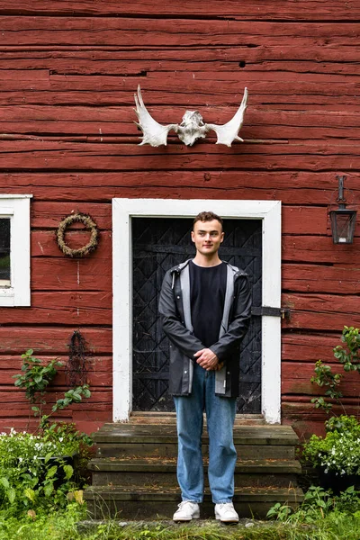 Skelleftea, Sweden A young man stands under a pair of antlers on a barn.