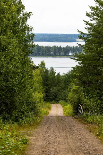 Burtrask, Sweden A dirt road in the woods and the Burtrask  lake in the distance.
