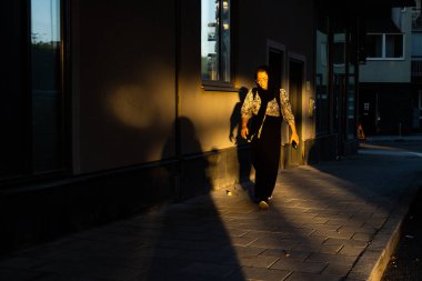 Stockholm, Sweden A woman walks along a street with strong morning light.