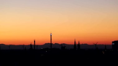 Copenhagen, Denmark Sunrise over the skyline with wind turbines spinning.